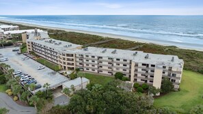 Ein mehrstöckiges Hotel mit Parkplatz und Blick auf den Strand.