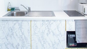A kitchen with marble countertops, a stainless steel sink, and a built-in microwave.
