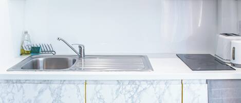 A kitchen with marble countertops, a stainless steel sink, and a built-in microwave.