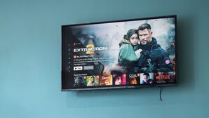 A television mounted on a teal wall displaying a Netflix movie titled "Extraction."