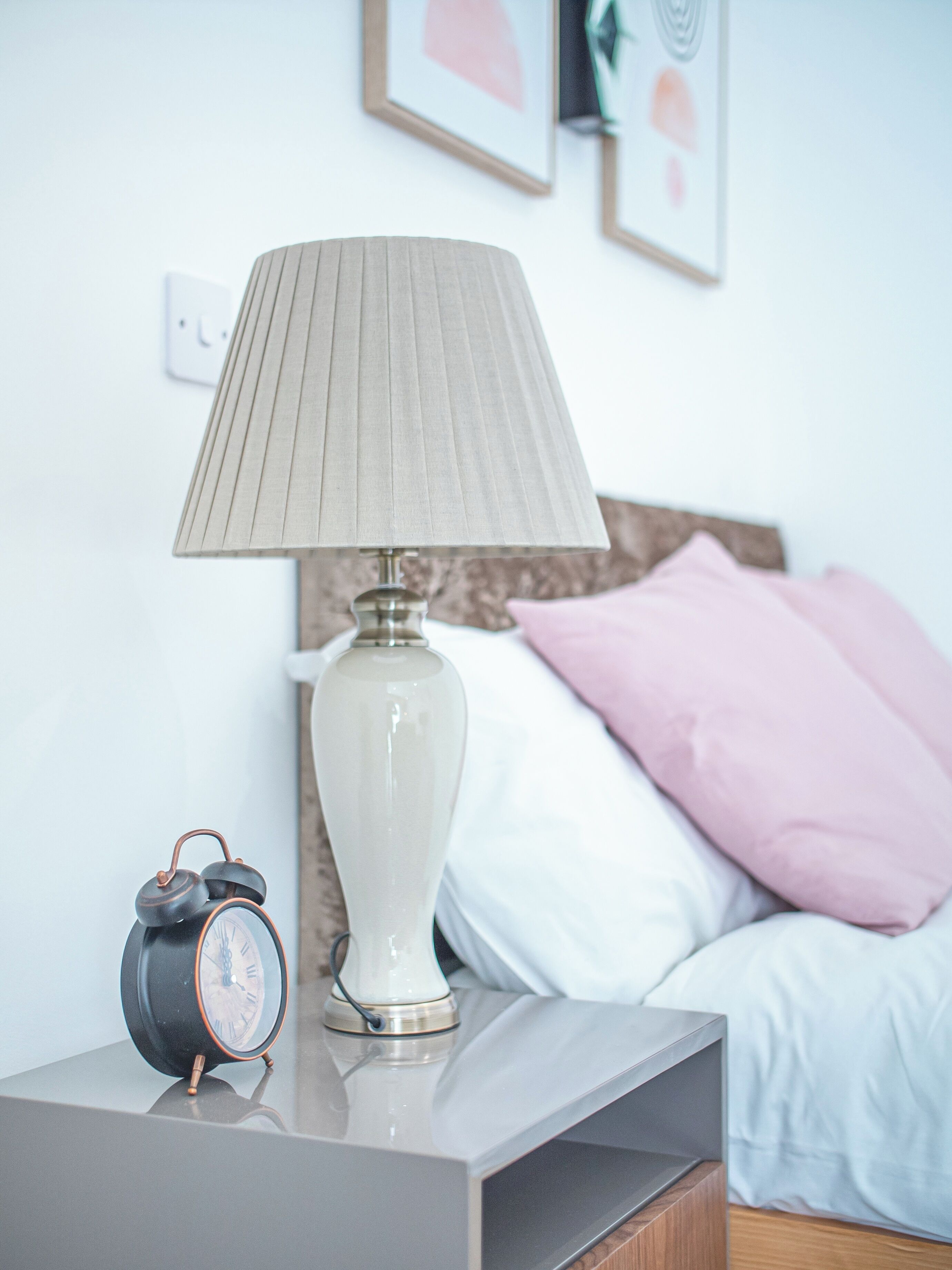 A bedside table with a lamp and an alarm clock.