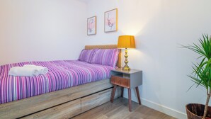 A bedroom with a bed, a nightstand, a lamp, and a potted plant. - Priestley Street Apartment in Sheffield (Sheffield)