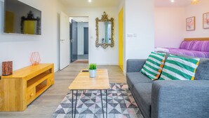 A modern living room with a sofa, a coffee table, a TV, and a mirror. - Priestley Street Apartment in Sheffield (Sheffield)