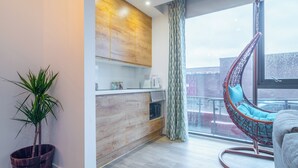 A modern kitchen with wooden cabinets, a hanging chair, and a potted plant. - Priestley Street Apartment in Sheffield (Sheffield)