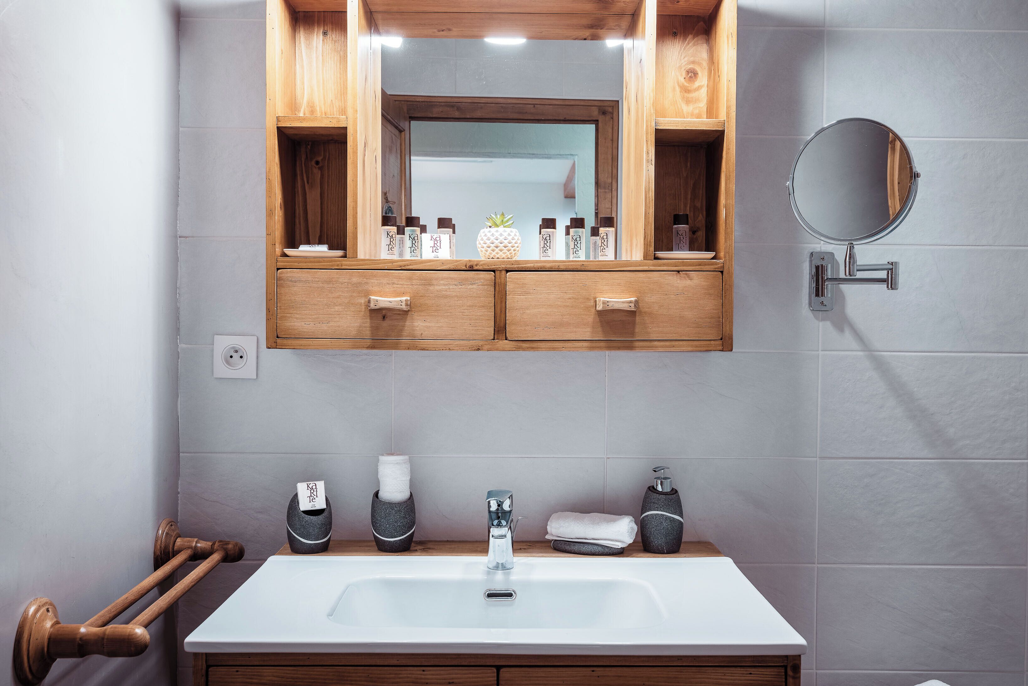 A bathroom with a wooden vanity, a mirror, and a sink.