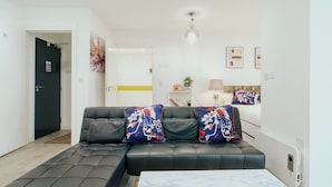 A modern living room with a sectional sofa, a coffee table, and a door leading to another room. - Lovely Triple Studio in Sheffield City Centre (Sheffield)