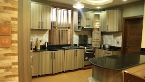 A modern kitchen with wooden cabinets, a black countertop, and a built-in oven. - Kigali Nice Apartment  (Kigali)