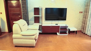 A living room with a sofa, TV stand, and wooden flooring. - Kigali Nice Apartment  (Kigali)