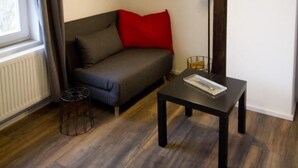 A modern living room with a sofa, a table, and a floor lamp. - NEW! Apartment Märchenstube (Alsfeld)