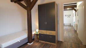 A bedroom with a wooden ceiling, a bed, a wardrobe, and a nightstand with a lamp. - NEW! Apartment Märchenstube (Alsfeld)