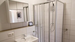 A bathroom with a white sink, mirror, and shower enclosure. - NEW! Apartment Märchenstube (Alsfeld)