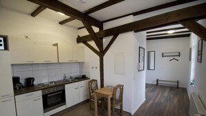 A kitchen with white cabinets, a wooden table, and chairs. There is a wooden ceiling beam structure. - NEW! Apartment Märchenstube (Alsfeld)