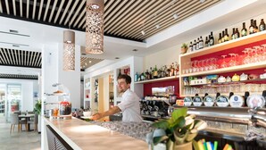 A modern bar area with a bartender, shelves of liquor bottles, and a tea display. - Vacation park Residence Village Mobilehome Happy Relax for 6 persons (Cavallino Treporti)