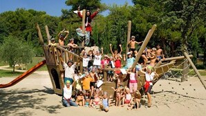 Un gruppo di persone riunite attorno a una struttura giochi in legno in un parco.