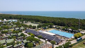 Ein Luftbild eines Küstenresorts mit großem Schwimmbad, Solaranlagen und einem Strand im Hintergrund.
