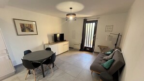 Una sala moderna con una mesa redonda de comedor, un sofá y un televisor.