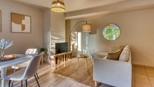 Ein modernes Wohnzimmer mit Essbereich, einer Couch, einem Fernseher und einem großen Fenster.