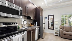 Une cuisine moderne dotée d’appareils électroménagers en acier inoxydable, de meubles de cuisine en bois foncé et d’un plan de travail de couleur claire.