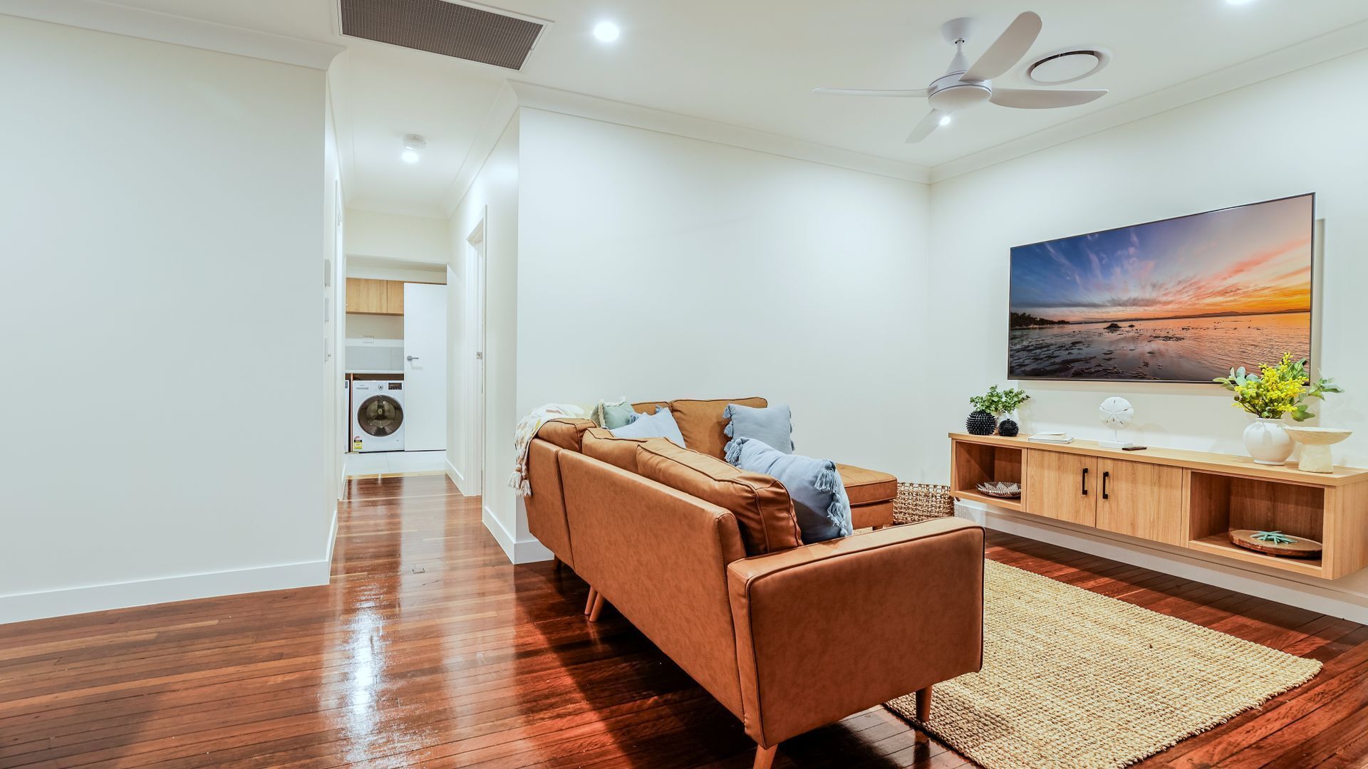 Uma sala de estar moderna com um sofá, uma televisão de tela plana e um quadro.