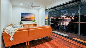 Una sala de estar moderna con un sofá, una mesa de centro y un ventanal que da a un balcón con mobiliario exterior.