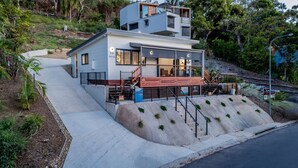 Una casa moderna de dos pisos con techo plano, ventanas amplias y un balcón.