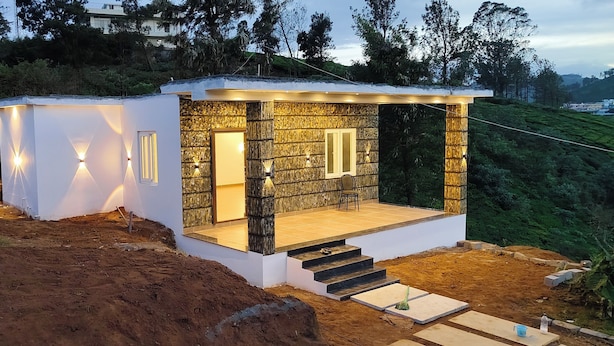 Ett modernt hus med en fasad av sten, en liten veranda och en trappa som leder upp till entrén.