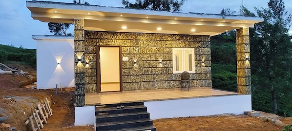 Una casa moderna con fachada de piedra, un porche cubierto y una escalera que conduce a la entrada.