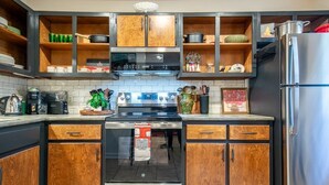 Una cucina moderna con mobili in legno, elettrodomestici in acciaio inossidabile e una parete rivestita in piastrelle.