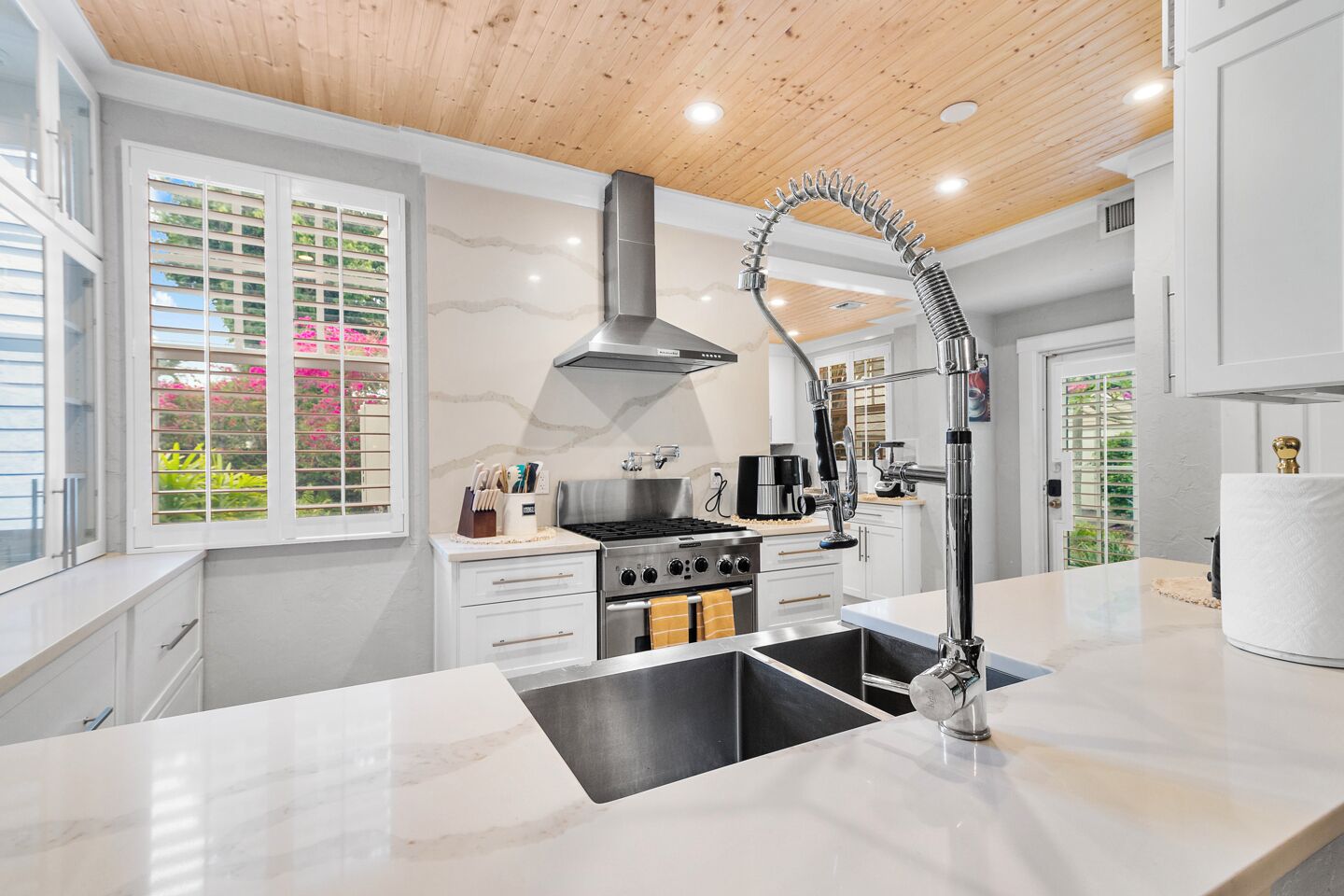 A modern kitchen with a central island, stainless steel appliances, and a high ceiling with wooden beams.