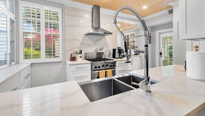 Una cocina moderna con una isla central, electrodomésticos de acero inoxidable y un techo alto con vigas de madera.