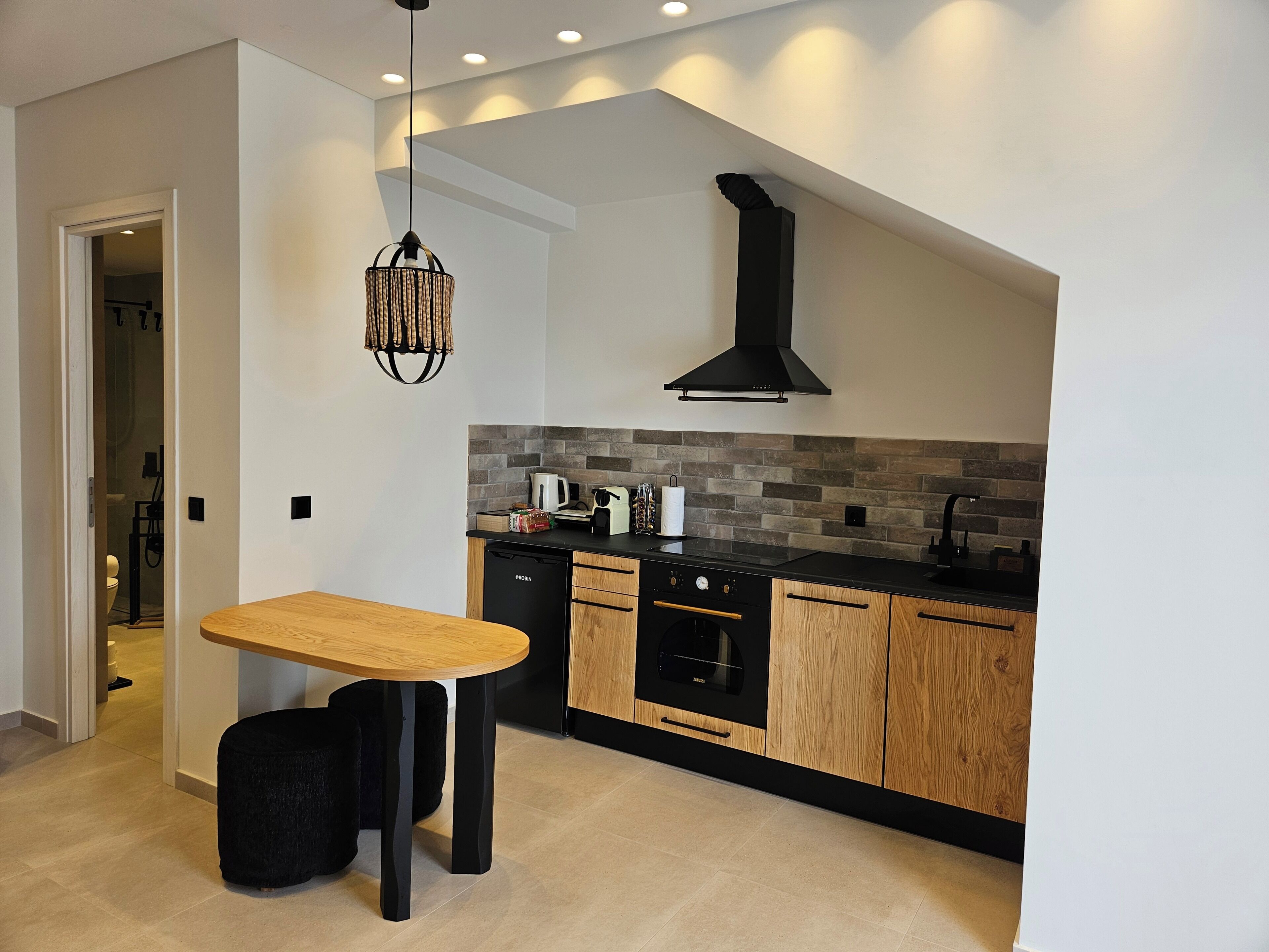 Una cocina moderna con una mesa de madera, armarios negros y una campana extractora negra.