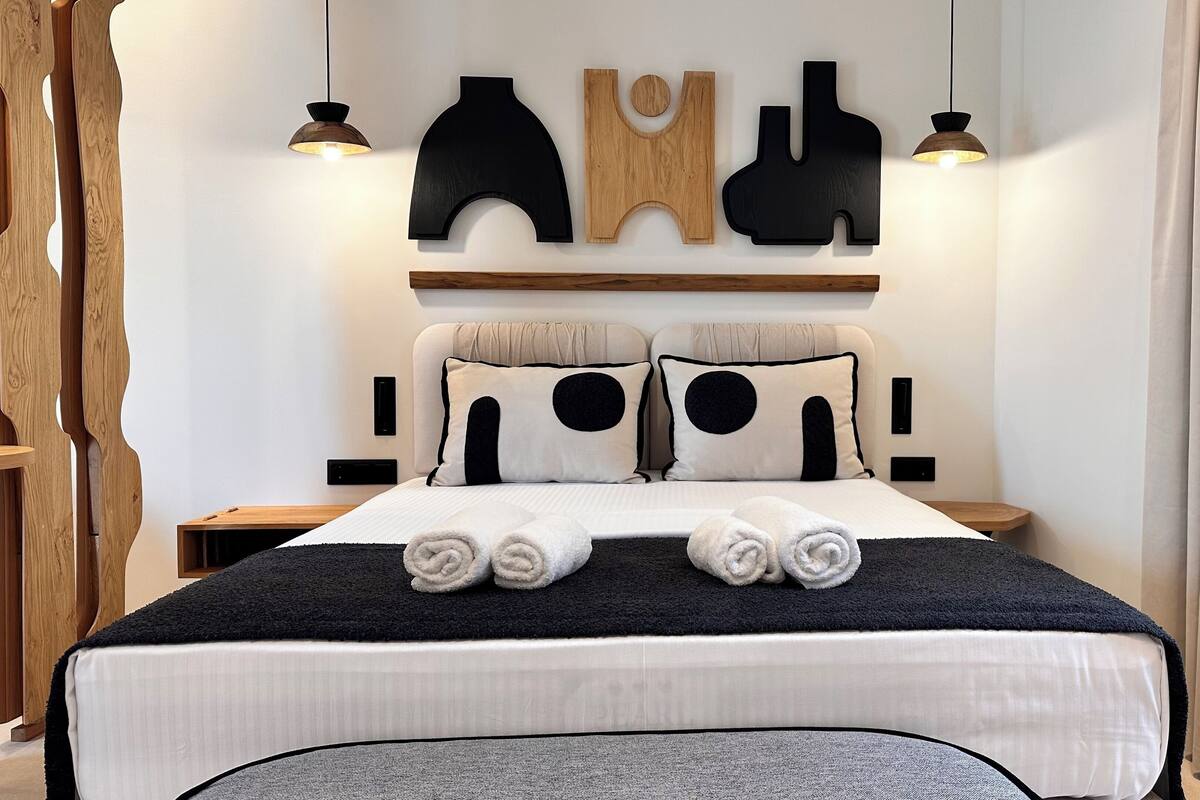 Ein modernes Hotelzimmer mit einem ordentlich bezogenen Bett, zwei Nachttischen und einem an der Wand befestigten Regal über dem Bett.