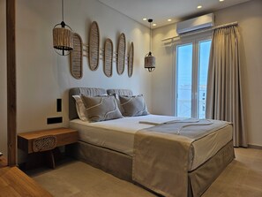 Ein modernes Schlafzimmer mit einem großen Bett, einem Nachttisch aus Holz, einer Bank und einer Wandleuchte.