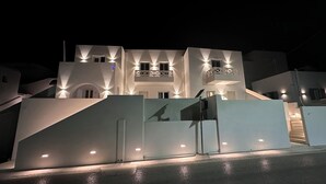 Ein modernes Gebäude mit einer markanten Treppe, die zu einem Balkon führt, beleuchtet von Außenbeleuchtung.