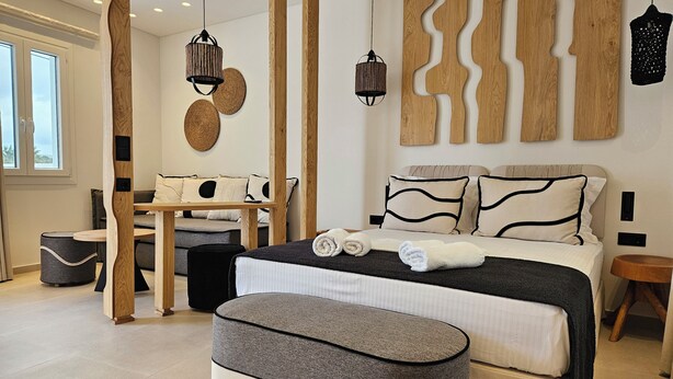 Ein modernes Hotelzimmer mit einem großen Bett, einer Wandpaneele aus Holz, einem runden Esstisch und einem kleinen Beistelltisch.