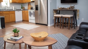 A modern kitchen with wooden cabinets, stainless steel appliances, and a dining area with two bar stools. - Boot Scoot'n In the Stockyards. 3 bedrooms/2 bath (Fort Worth)