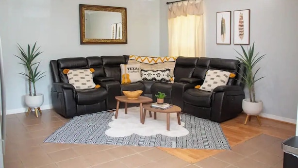 A living room with a sectional sofa, two side tables, a rug, and two potted plants. - Boot Scoot'n In the Stockyards. 3 bedrooms/2 bath (Fort Worth)