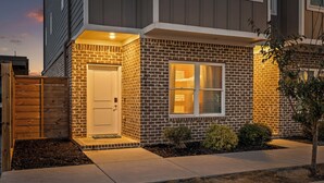 A residential building with a brick exterior, a front door, and a window. - Lookout Getaway: Luxury 4 Bedroom, Rooftop Deck (Chattanooga)