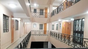 Un pasillo de varios niveles con una escalera central, barandillas de metal y puertas que dan a habitaciones.