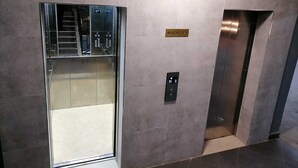 Un ascensor con pantalla digital, un letrero que indica 'Sótano 1' y una puerta de cristal.