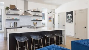 Une cuisine moderne dotée d’un îlot central, de tabourets de bar et d’un luminaire suspendu.
