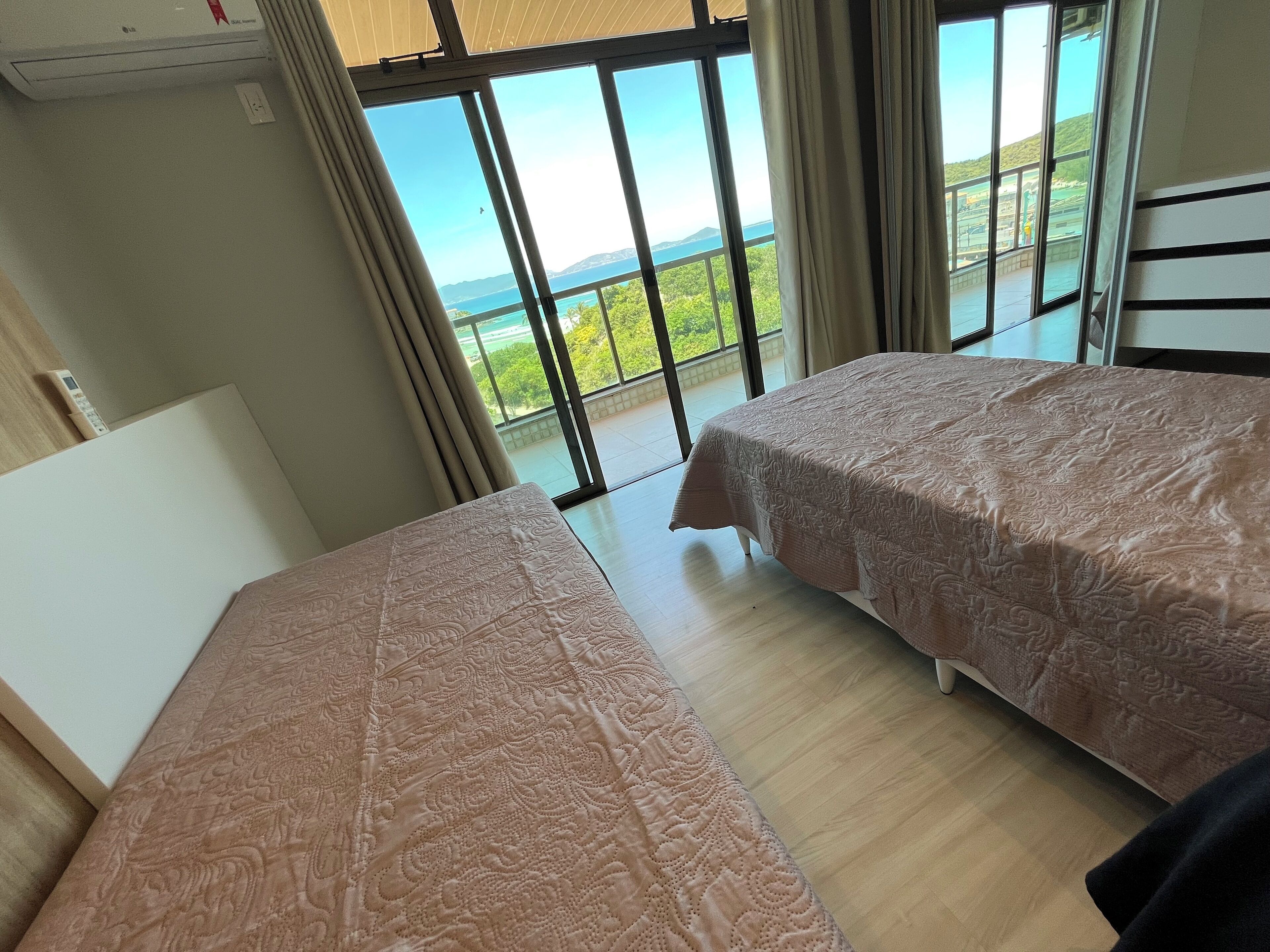 Een slaapkamer met twee bedden, grote ramen en uitzicht op zee.