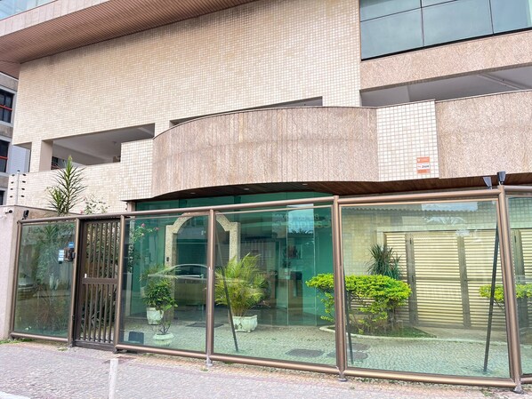 Ein modernes Gebäude mit gewölbter Fassade, großen Glasfenstern und Pflanzen vor der Vorderseite.
