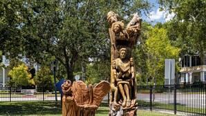 Una escultura de madera que muestra a una familia en un parque.