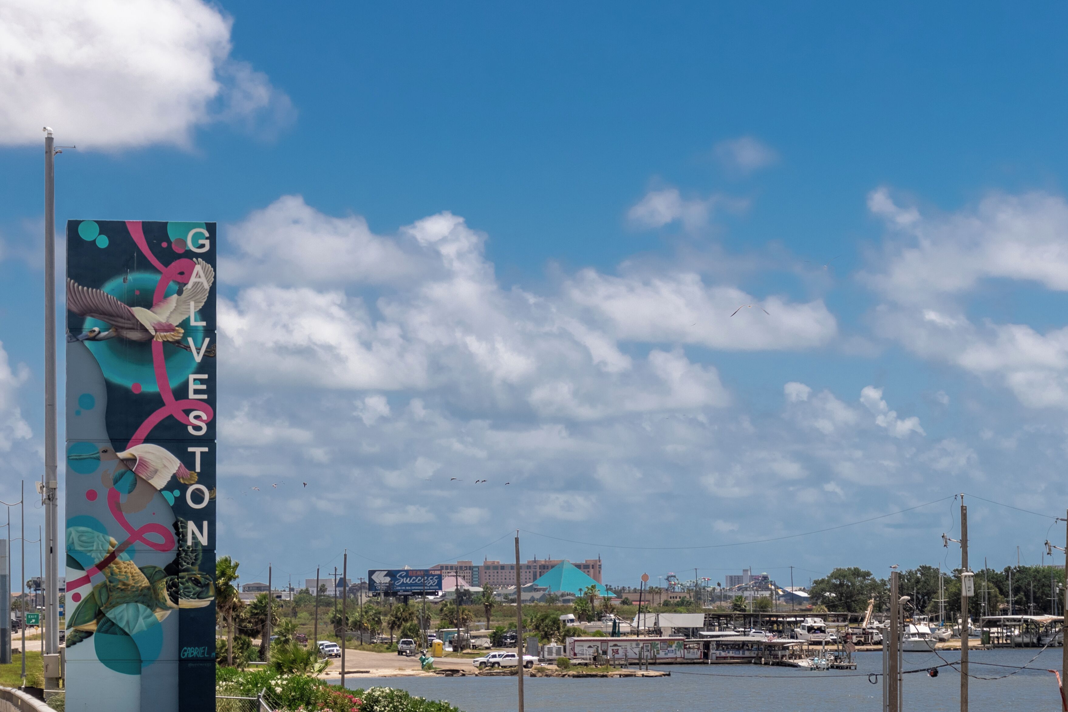 A waterfront view with a tall billboard featuring a bird and the text "GABRIEL STON".