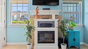 Un salón con chimenea, televisor y plantas en macetas.
