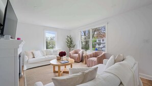 Una sala de estar moderna con un sofá blanco, una mesa de centro redonda y una chimenea.