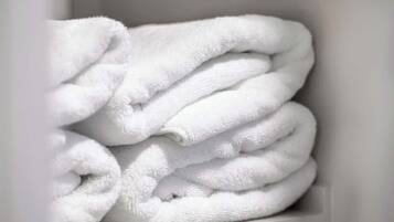 A stack of white towels in a white shelf.