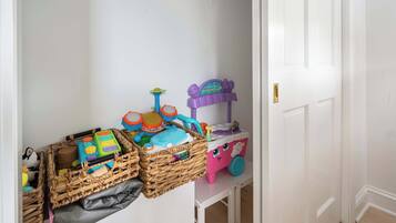 A room with a white door, a small table with toys, and wicker baskets filled with items.
