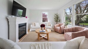 Una sala de estar con chimenea, televisor, un ventanal grande y dos sofás.